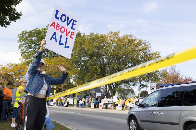 Mai Britt waves at passing cars Saturday, Oct. 18, 2025, during the “No Kings” protest in Sterling. Hundreds lined Fourth Street to demonstrate against President Trump.