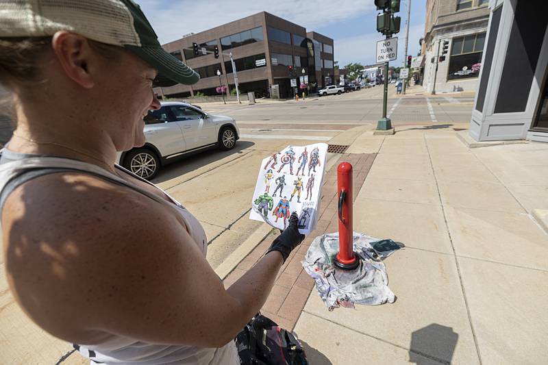 Reuter keeps a print out of the heroes in order to make sure the color schemes and details are correct Monday, June 24, 2024. She will paint 12 in all.