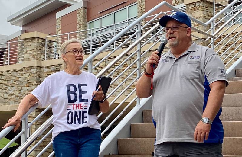 Cindy Hupke (left), member of the American Legion Post No. 66 Auxiliary and head organizer, watches while Joe Lampert, U.S. Navy veteran and department commander of the American Legion Department of Illinois, gives remarks about the importance of seeking help for mental crises. The remarks opened the inaugural Be the One Walk at Northwestern Medicine Health and Wellness Center on Sunday, Sept. 22, 2024, an event organized by DeKalb area veterans groups to raise awareness about veteran suicide rates.