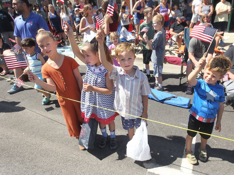 Layla Hagy, 7, of Tower Lakes, Eve Jackowski, 5, of Mundelein, Lee Hagy, 3, brother of Layla and their brother, Miles, 5, wave their flags Monday, May 29, 2023, on Main Street as they watch the Wauconda Memorial Day Parade. Eve's father, Aaron, served in the Air Force.
