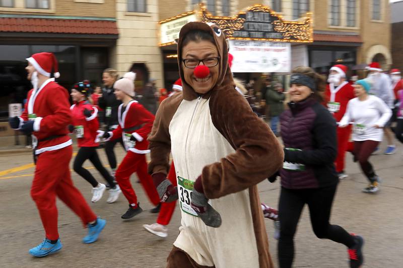 Tiffany Sittner dressed as a reindeer smiles as she runs with some to the over 500 Santa Claus dressed runners in 5K race during the McHenry County Santa Run For Kids Sunday morning, Dec. 3, 2023, in Downtown Crystal Lake. The annual event raises money for agencies in our county who work with children in need.