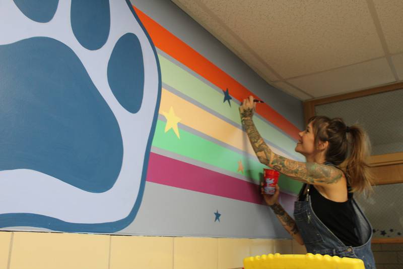 Parent Sara Jean Stevens puts on some finishing touches to one of the murals she painted at District 47's North Elementary School in Crystal Lake.