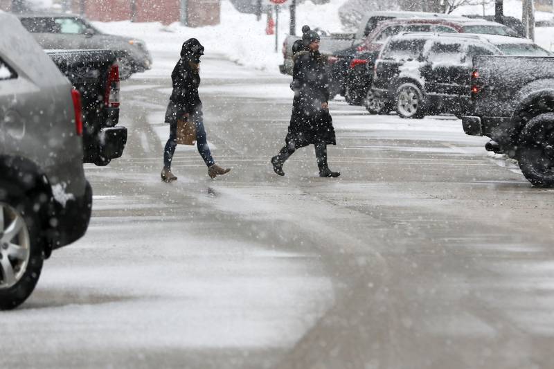 Pedestrians cross the street as snow falls downtown on Thursday, Feb. 4, 2021 in Crystal Lake.