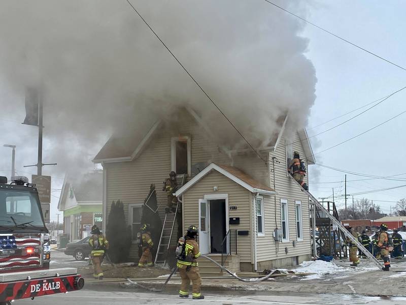 A firefighter on a ladder works to break the upstairs window to a two-story duplex to get water into the structure on Saturday, Jan. 24, 2026, at Seventh Street and East Lincoln Highway in downtown DeKalb. Fire Chief Luke Howieson said the rampant flames spread too quickly into the walls for it to be safe for firefighters to remain in the building.