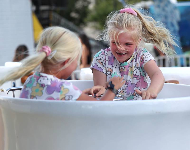 Avery Peterson, (right) 6, and her sister Harper, 4, from Sycamore, ride the teacups at the carnival Friday, Aug. 22, 2025, during the first day of Corn Fest in downtown DeKalb.