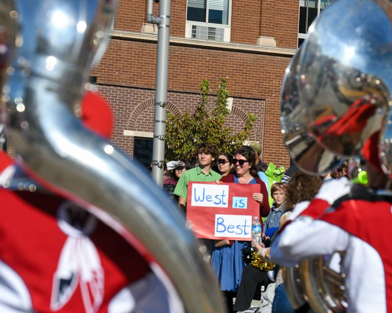 Julie Zaborac and her son Sam Jaros, 15, of DeKalb, hold a sign as the West Aurora marching band passes by during the Pumpkin Parade on Sunday Oct. 28, 2024, downtown at the 63rd annual Sycamore Pumpkin Festival.