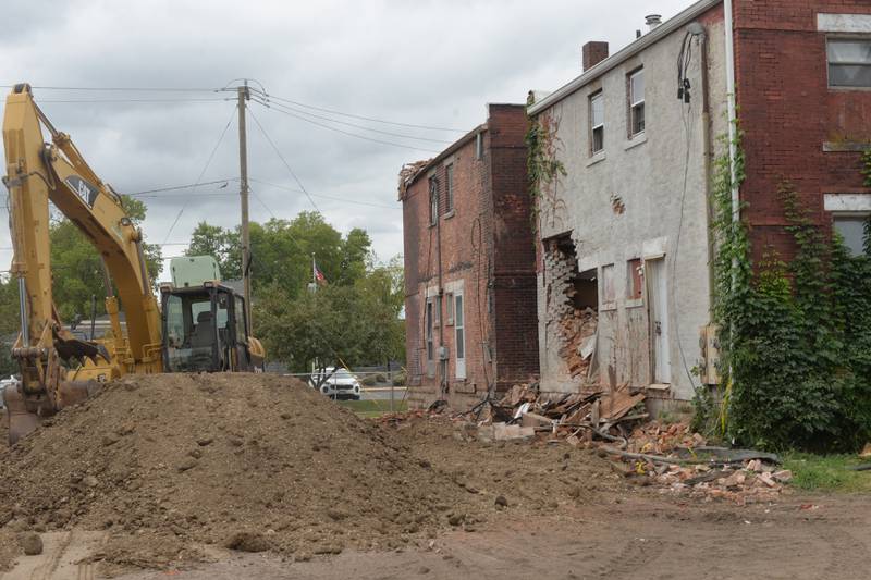 Am excavator sits where a 3-story apartment building was demolished following a July fire that also took the life of one tenant. Two apartment buildings on Fourth Avenue, located to the west of the building were also damaged.
