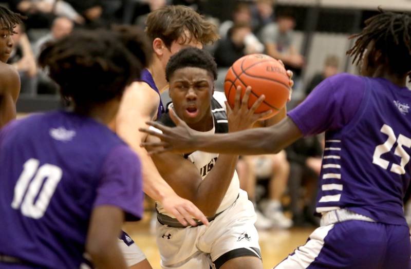Kaneland’s Gevon Grant (center) squeezes through the Plano defense during a game in Maple Park on Tuesday, Dec. 20, 2022.
