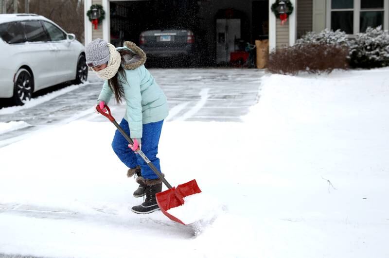 Alex Villa, 13, helps shovel the driveway of her Batavia home as temperatures dip below zero on Friday, Dec. 23, 2022.