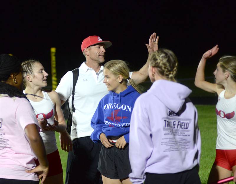 Oregon track coach Nick Schneiderman gives Grace Tremble a high five after she ran the anchor leg of the 4x400 relay at the 1A Lena-Winslow sectional on Thursday, May 15, 2025.The Hawks were sectional champions.