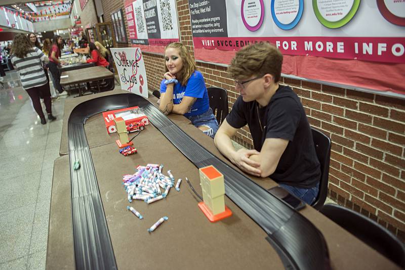 Sauk Valley Community College science club members Sophia Terry and Kyle Lapp sit at a booth Wednesday, April 20, 2022 during Sauk Fest. The club had set up a track with cars that raced on kinetic energy.