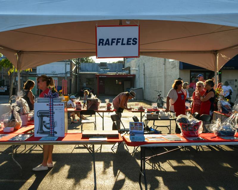 Julie Hanebuth, center, of Elmhurst fills out her raffle tickets during the Cue for a Cause event on Sunday Sep. 1, 2024, in downtown Elmhurst.