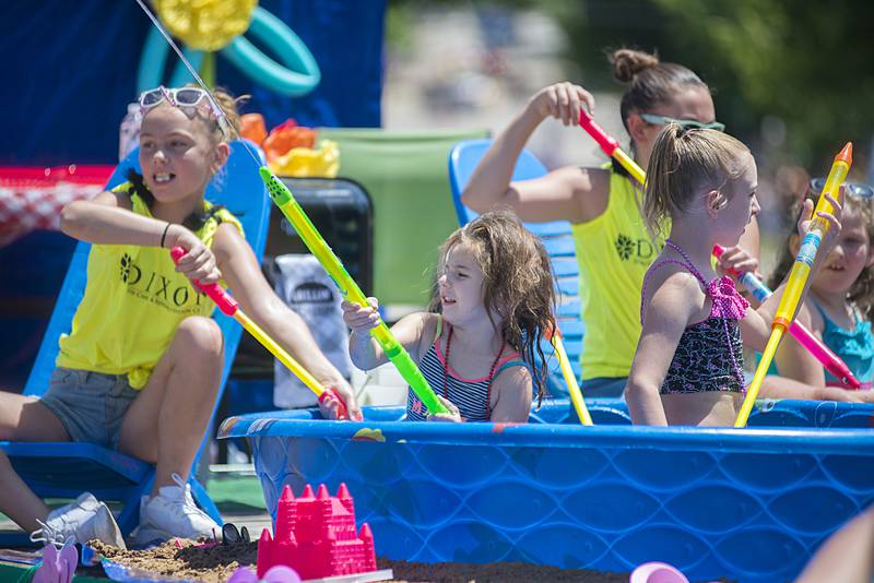 Dixon Rehabilitation and Health Care representatives use water siphon toys to send welcoming jet steams of cool water toward spectators on Sunday during the Petunia Festival parade.