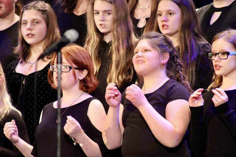 Reagan Middle School choir members snap their fingers to mimic the sound of rain splattering on pavement during its rendition of "Listen to the Rain" as part of Choir Fest on Friday, March 3, 2023.