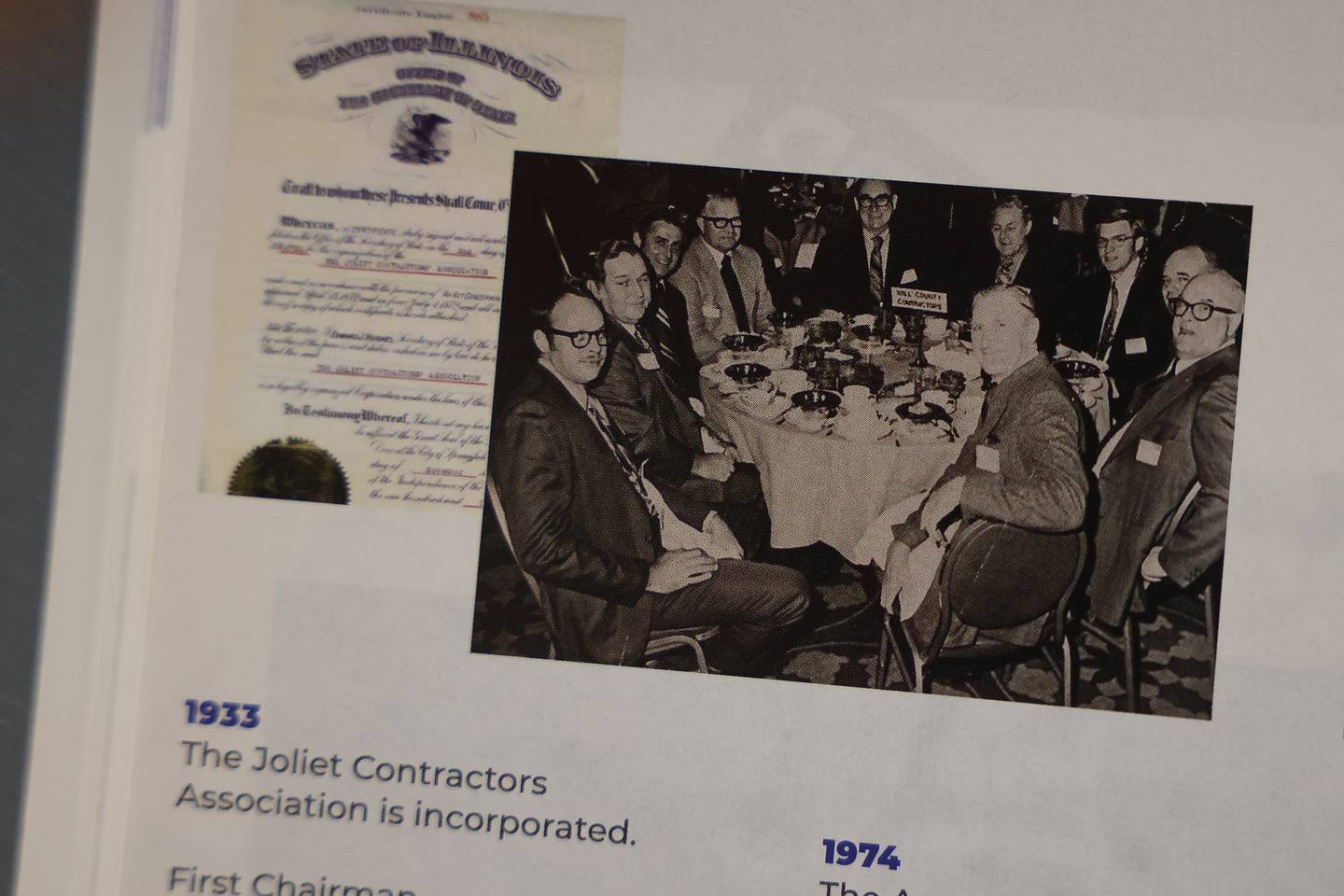 Several photos, one of the certification for becoming incorporated and another of the 1974 merging of the Will and Grundy County Contractors Association appear in a magazine in the lobby of the Contractors Association of Will and Grundy Counties on Wednesday, Nov. 1, 2023 in Joliet.