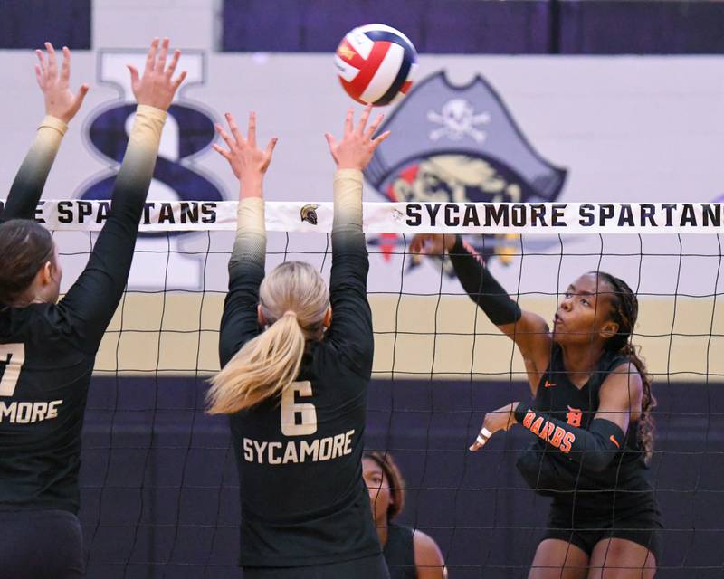 DeKalb's Amaya Kemp, right, spikes the ball past two Sycamore defenders on Wednesday Aug. 27, 2025, held at Sycamore High School.