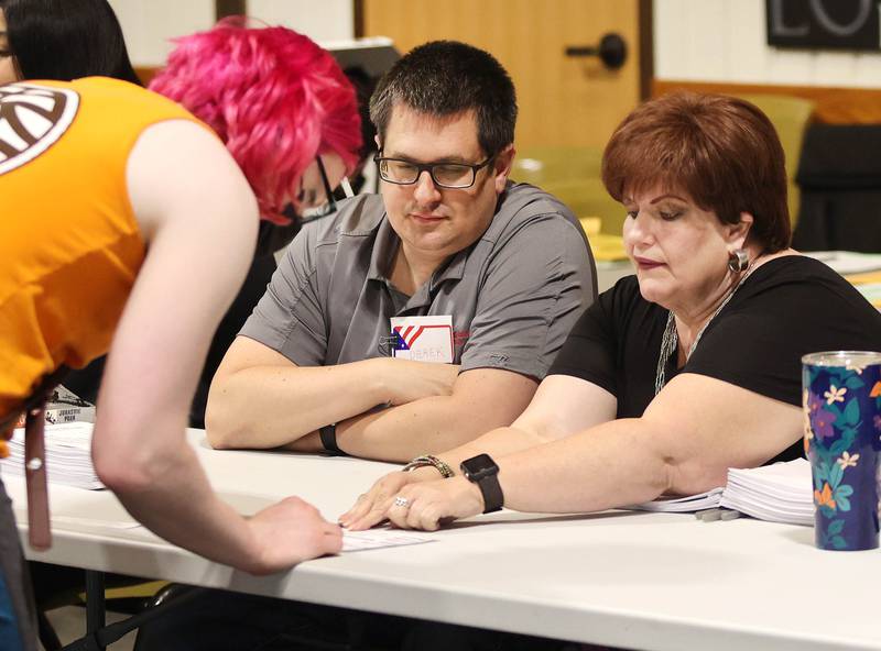 Election judges Derek Shaw (left) and Tamara Person-Hescott help Nicc Misner, of DeKalb, get checked in prior to voting Tuesday, June 28, 2022, at the polling place in Westminster Presbyterian Church in DeKalb.