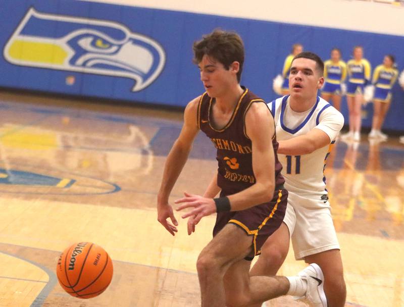 Richmond-Burton’s Dane Gardner, left, scoots past Johnsburg’s Ryan Franze in varsity boys basketball onTuesday, Dec. 9, 2025, at Johnsburg High School in Johnsburg.