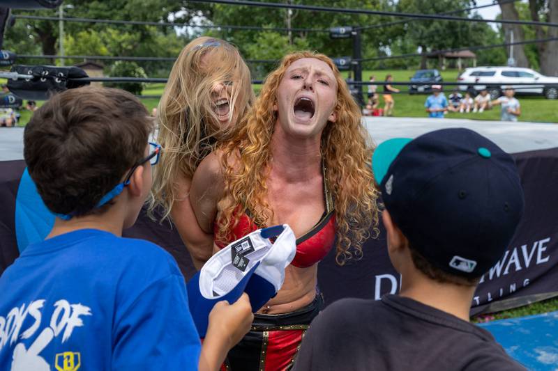 (left to right) Rebecca J. Scott holds Maggie Lee as fans taunt her at the Taste of the Illinois Valley DreamWave Wrestling event on Saturday, August 2, 2025 at Centennial Park in Peru.