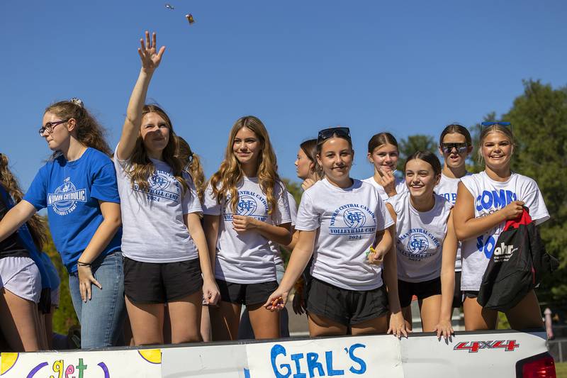 Newman volleyballers wave and throw candy Friday, Sept. 20, 2024, during the homecoming parade.