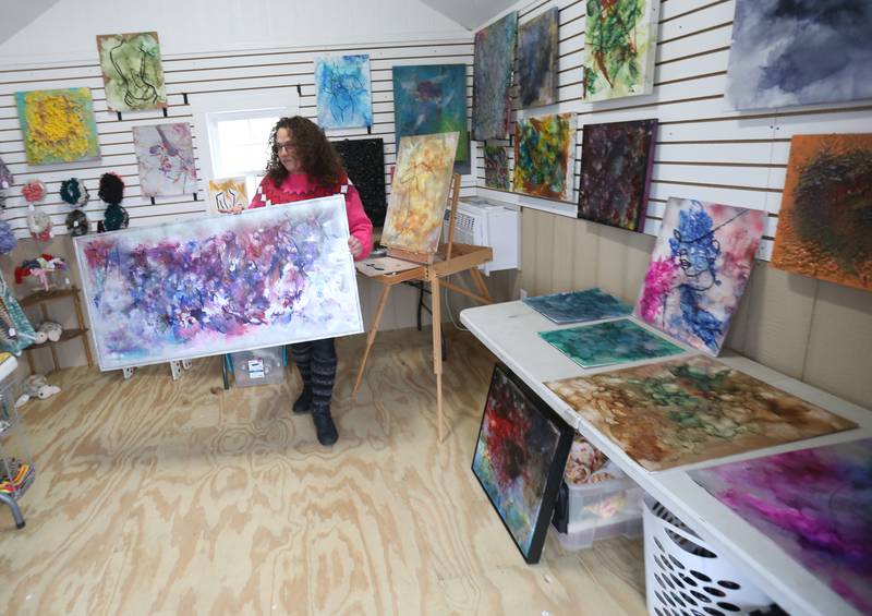 Lisa Marie, hair stylist and abstract artist, shows off her fire paintings inside a hut on Saturday, Feb. 8, 2025 at the Market On Mill plaza in Utica. Marie painted items and sold them at the Winter Wine Walk.