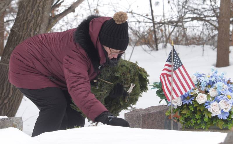 Laurie Carlin-Perry places a wreath on a veteran's grave during the Wreaths Across America program at the Daysville Cemetery, southeast of Oregon, on Saturday, Dec. 13, 2025.