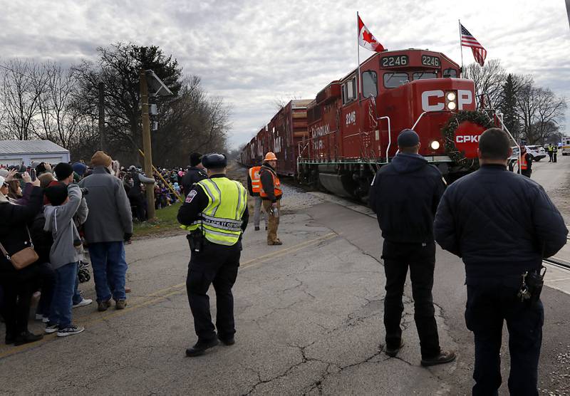 Police and railroad official guard the tracks  on Wednesday Nov. 27, 2024, as the Canadian Pacific Kansas City Railway 2024 Holiday Train pulls into Pingree Grove. The holiday train raised food and monetary donations for the D300 Food Pantry during its stop in Pingree Grove.