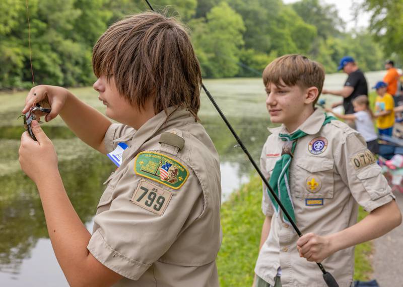 Scout Warren Jones (left) helps his friend Nathan Fessler get a deep hook out of Fessler's catch during the 38th Annual Kid's Free Fishing Tournament on June 7, 2025 at Lock 14 in La Salle.