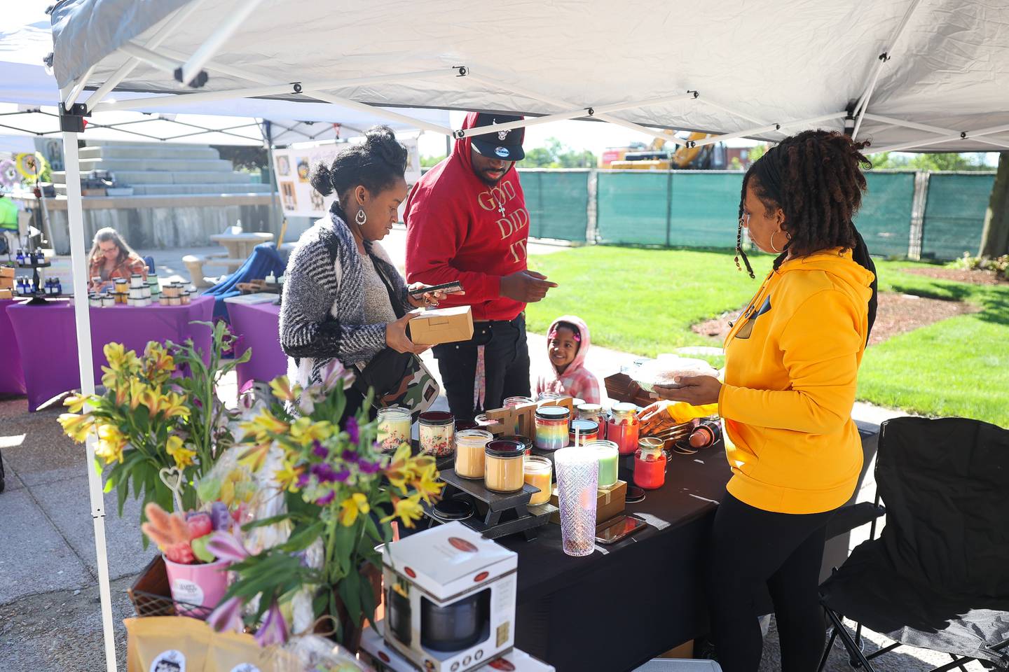 Nicole Kincaide, left, purchases an item from Lit Candles as her husband Timothy and daughter Trinity continue to browse at the weekly Farmers Market in downtown Joliet on Saturday, May 11, 2024.
