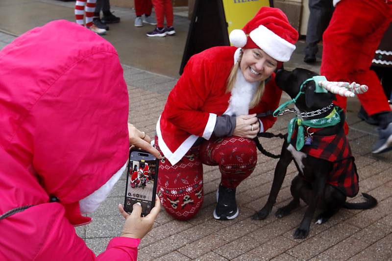 Kim Macygin gets a list from Molly as she has her picture taken before the start their 5K race during the McHenry County Santa Run For Kids on Sunday morning, Dec. 3, 2023, in Downtown Crystal Lake. The annual event raises money for agencies in our county who work with children in need.