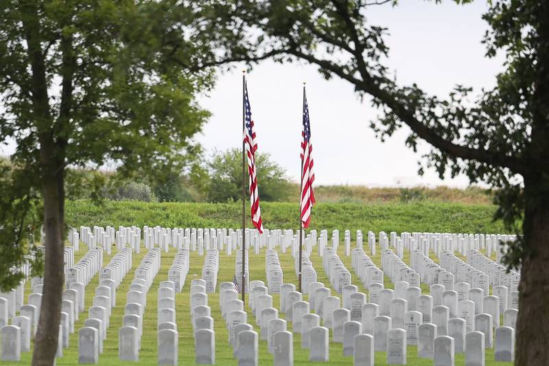 Two American flags fly over headstones of members of the armed forces at the Abraham Lincoln National Cemetery in Elwood on Saturday, July 29.