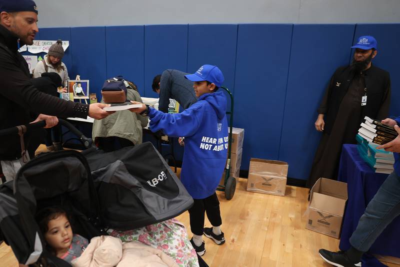 Syed Nuh Ahmed hands out free copies of the Quran to supporters as the enter the gym for a vigil for Wadea Al-Fayoume at Prairie Activity & Recreation Center on Tuesday, Oct. 17, 2023 in Plainfield.