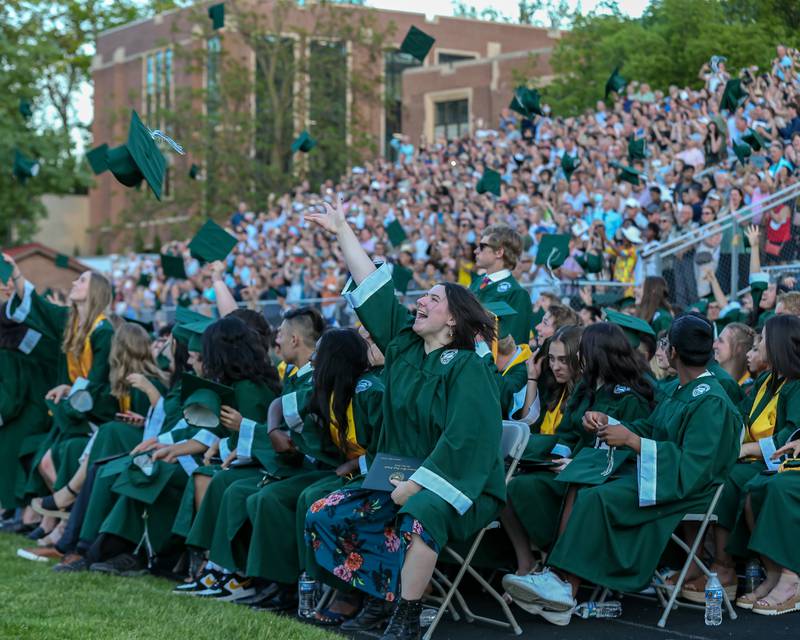 Students toss their caps after receiving their diplomas during the Glenbard West High School graduation ceremony. May 19, 2022