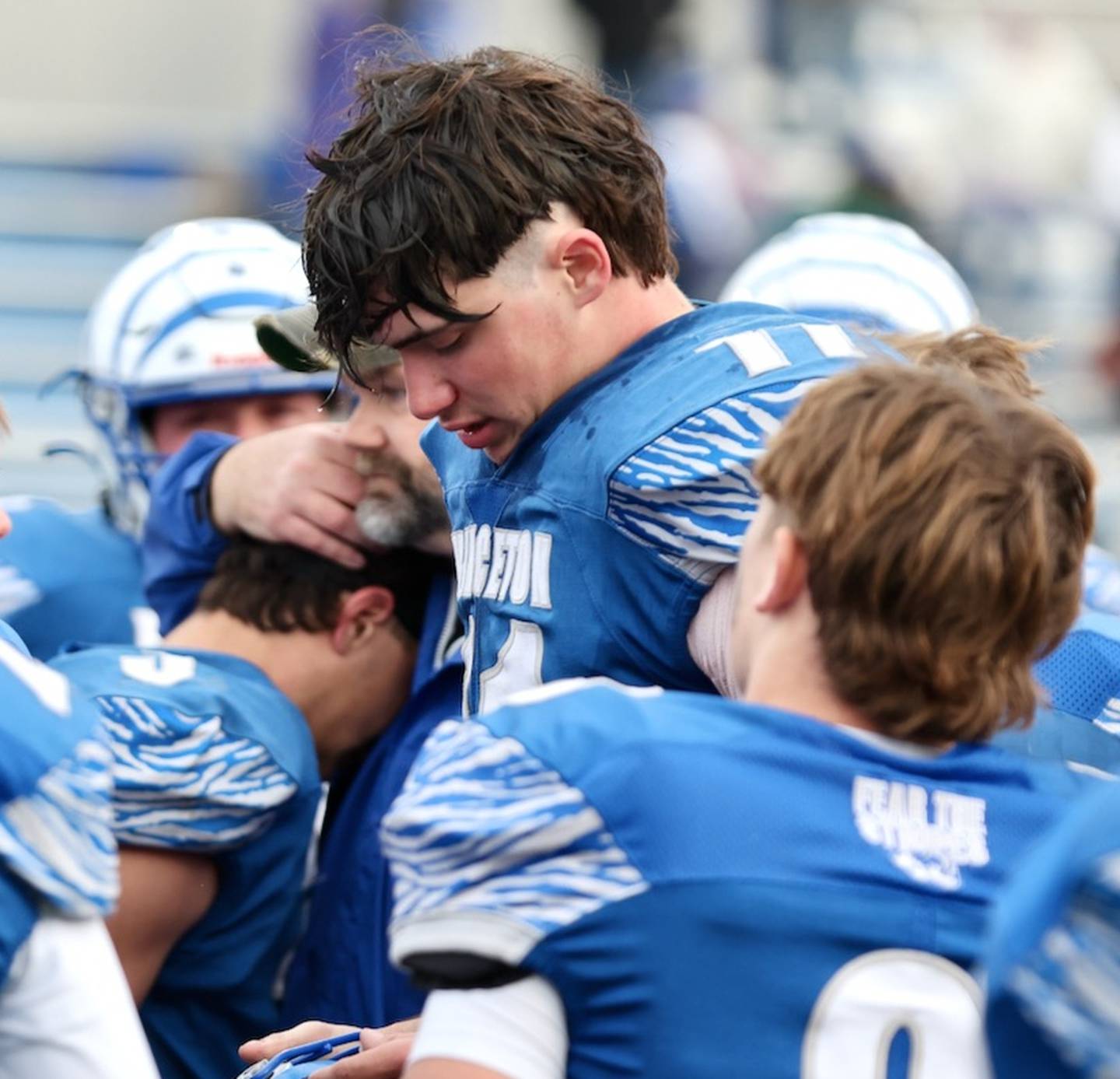 Princeton senior Noah LaPorte (11) collects his thoughts while classmate Ace Christiansen receives a hug from coach Ryan Pearson following the Tigers' 24-7 loss to Lombard Montini in Saturday's quarterfinals at Bryant Field.