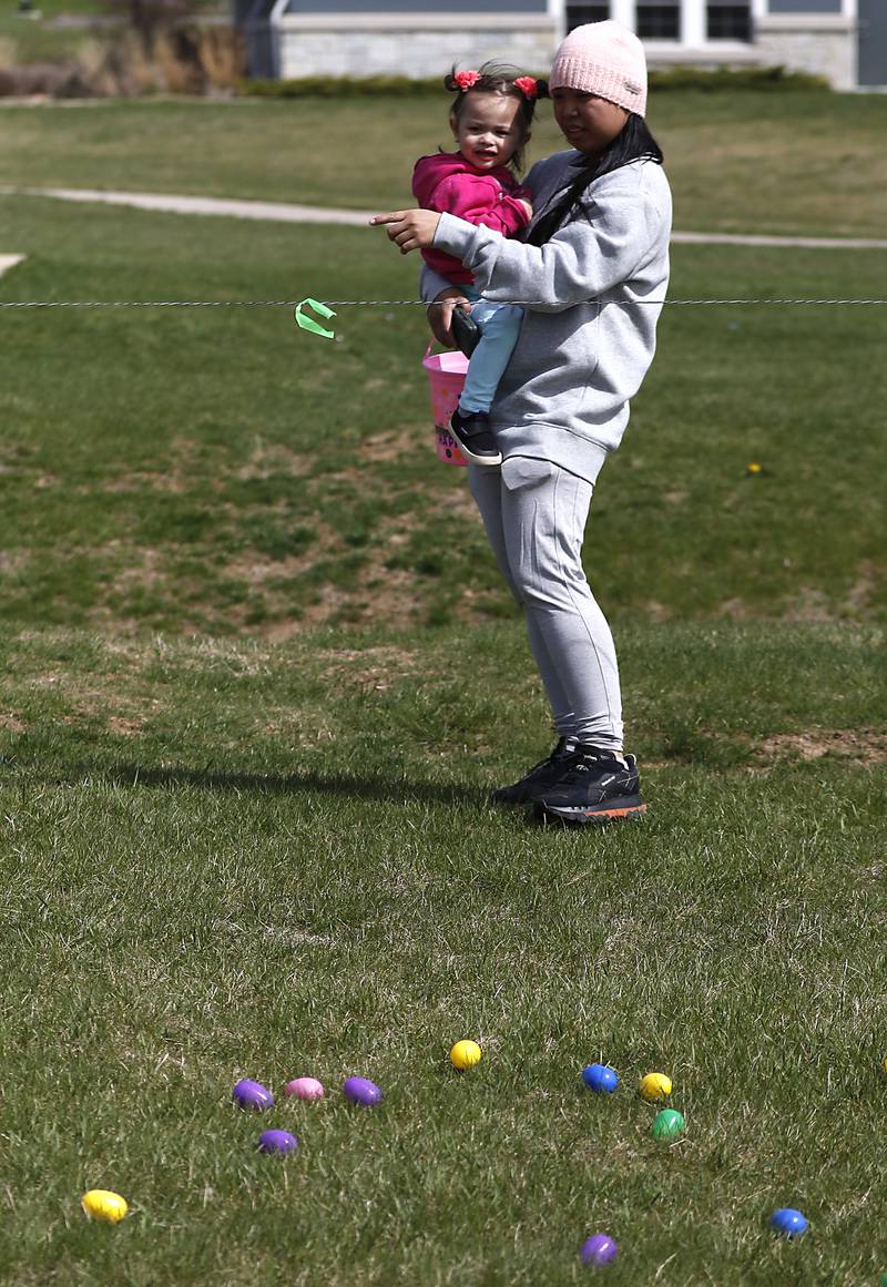 Daylene Miller, points out eggs to grab to her daughter, Rylee, 2,  on Saturday, April 19, 2025, during the Johnsburg Easter Egg Hunt at Sunnyside Memorial Park, in Johnsburg. Children hunted for 6,000 candy-filled eggs in three hunts divided by age group.