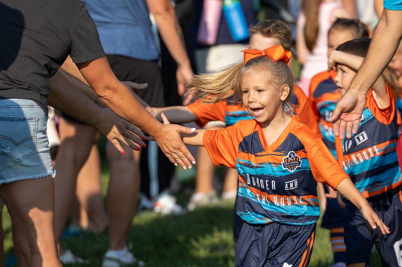 Ella Carmona high-fives friends and family attending the opening day ceremony of youth soccer on Saturday, Aug 16, 2025, at Peck Park in Ottawa.