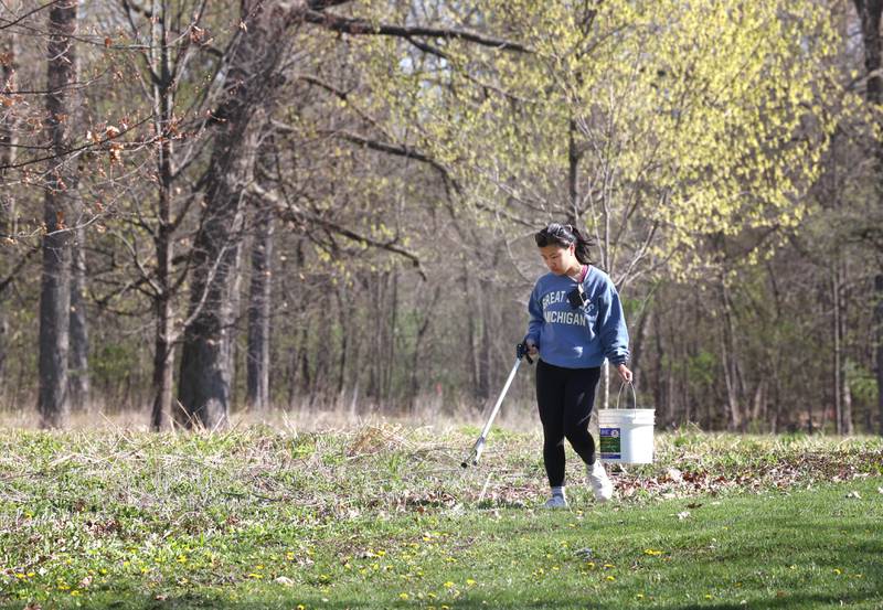 Emma Asta, from Downers Grove, looks for trash as she walks Monday, April 22, 2024, during an Earth Day Clean Up event at Hopkins Park in DeKalb.