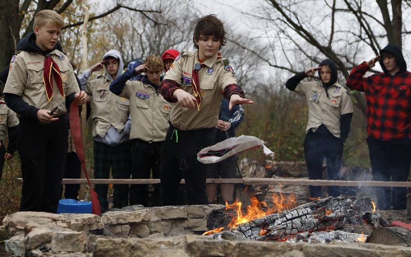 A boy scout from St. Charles Troop 1 throws a cut stripe of the American flag into the fire during the Annual Veterans Day Scout VFW vigil and flag retirement ceremony at Overseas VFW Post 1197 in Batavia on Saturday Nov. 5, 2022.