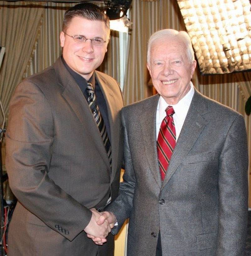 Voice of America reporter Kane Farabaugh shakes hands with former president Jimmy Carter, who he had interviewed one-on-one more than 20 times.