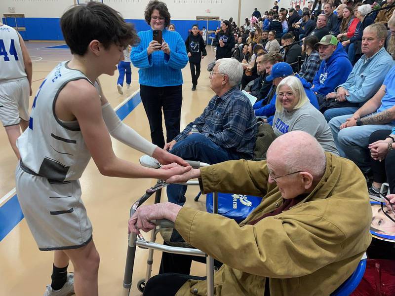 Former athletic coach Bob Long, 98, of Joliet (right), shakes the hand of St. Jude Catholic School basketball player Joaquin Berman at the school's final home game on Feb. 15.