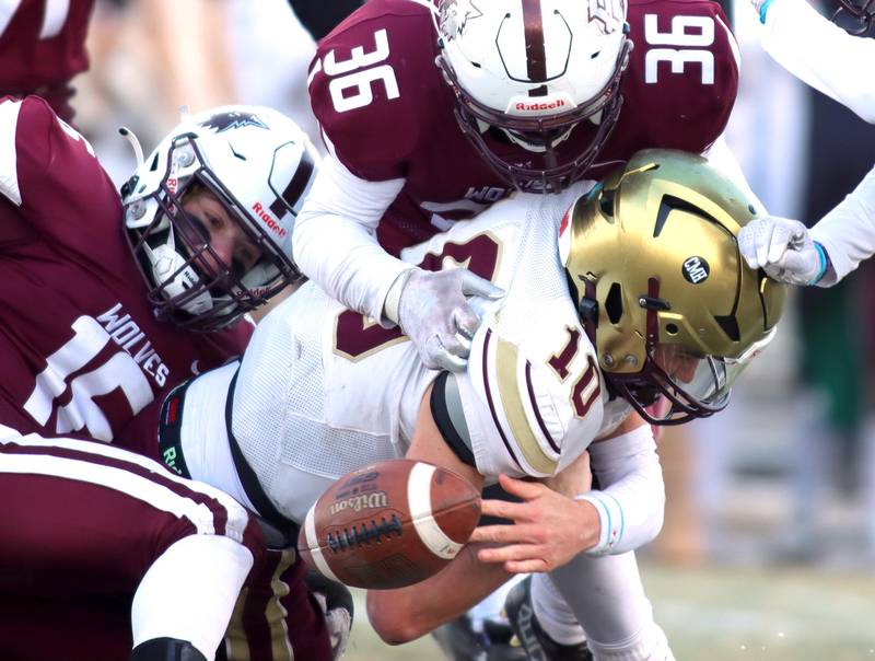 Prairie Ridge’s Dominic Creatore, left, and Giovanni Creatore, top, hit St. Ignatius’ Jake Petrow as the ball pops loose in Class 6A football playoff semifinal action at Crystal Lake on Saturday.