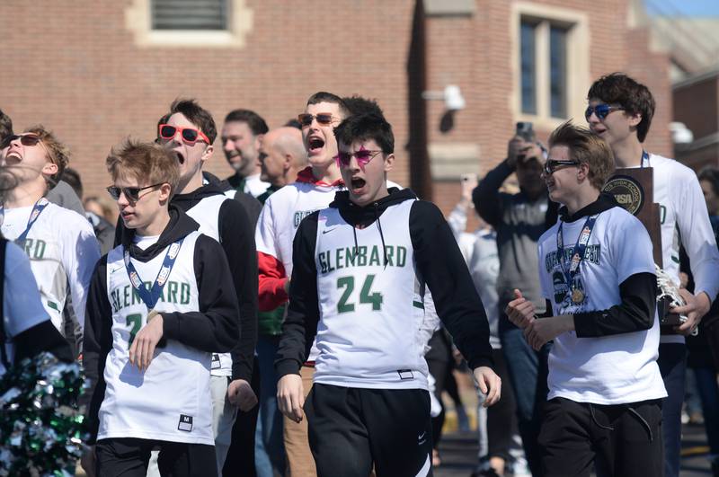 Glenbard West state basketball players including Paxton Warden walk with the marching band down the hill of the school to Biester Gym to celebrate their state chamionship during the pep rally held Sunday March 13, 2022.