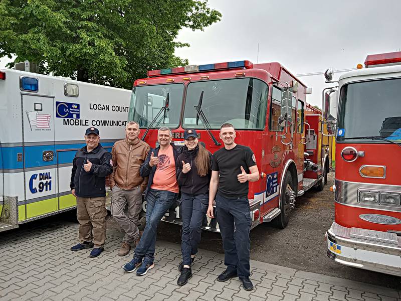 Crew members of the donated firetruck stand in front of the engine to show their appreciation.