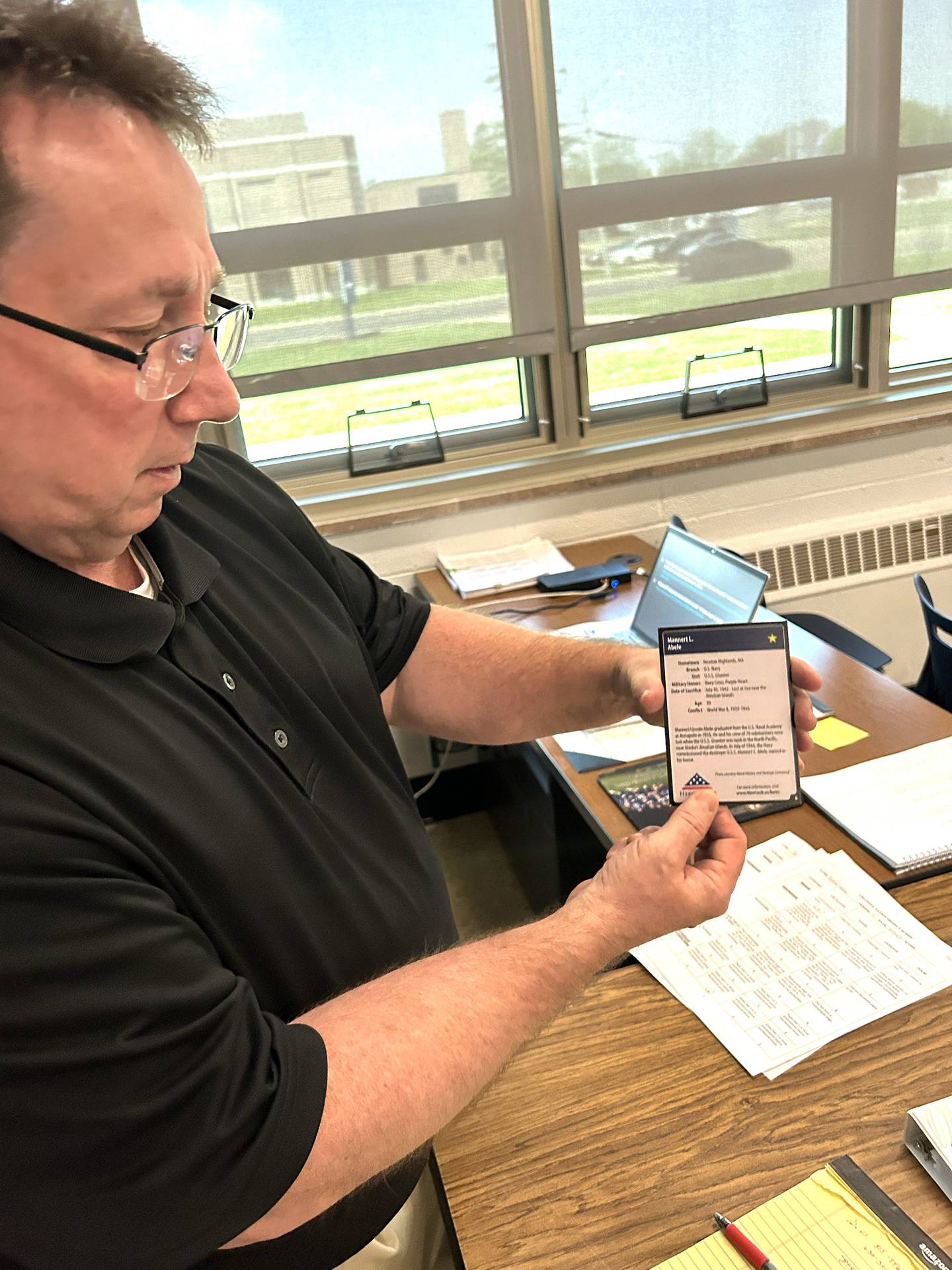 Social studies teacher Jeff Bargar holds one of the "Hero Cards" on Thursday, May 15, 2025 during presentations by his students as part of The Grateful Nation Project.