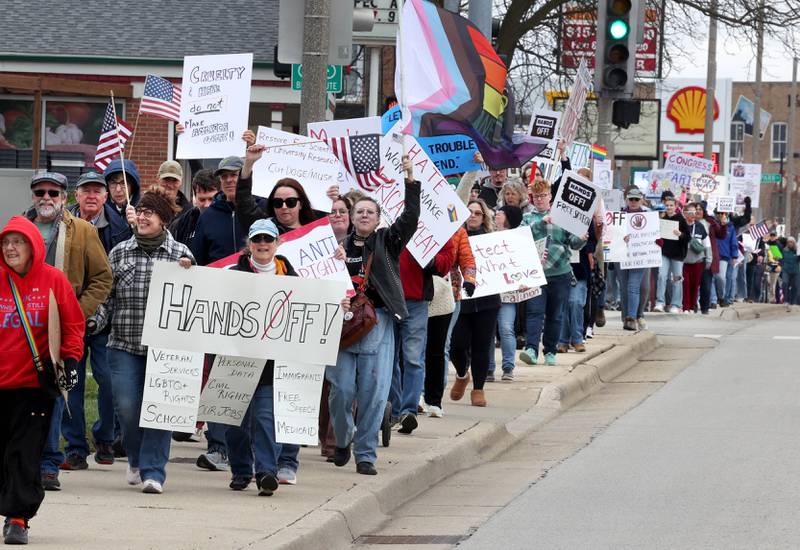 Protesters march down Lincoln Highway Saturday, April 5, 2025, during a Hands Off! rally in DeKalb. Hundreds of people gathered to protest against various policies of President Donald Trump and his administration.