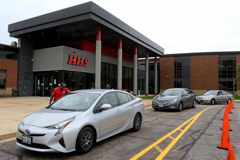 Huntley High School Principal Marcus Bellin greets students in a line of cars arriving to pick up their graduation materials June 3 at Huntley High School.