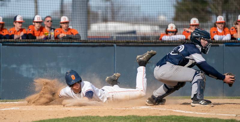 Oswego’s Trey Hernandez (14) slides into home head first beating the throw to score a run against Plainfield South during a baseball game at Oswego High School on Monday, April 11, 2022.
