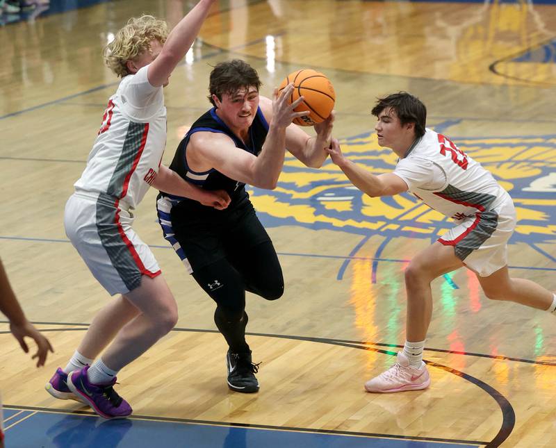 Hinckley-Big Rock's Martin Ledbetter drives between Aurora Christian's Asa Johnson (left) and Jacob Baumann during their sectional final game Friday, March 7, 2025, at Somonauk High School.