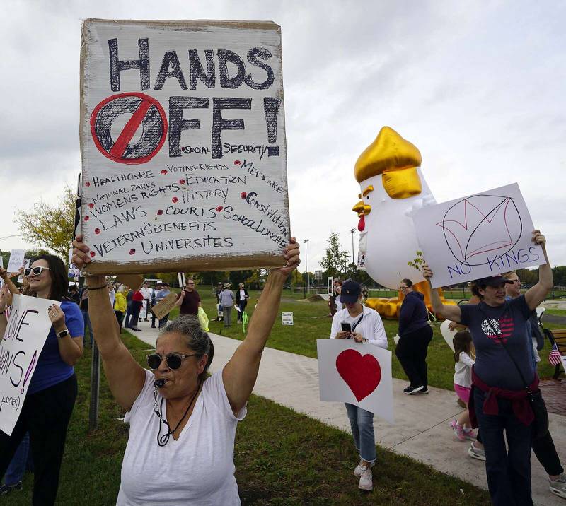 Francine Lombardo of Arlington Heights holds up her sign so drivers on Route 14 can see during the “No Kings” rally Saturday at Recreation Park in Arlington Heights.