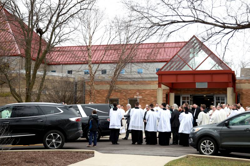 Clergy line the walkway as the casket of Reverend Jonathan Bakkelund is loaded into a hurse following the Mass of Christian Burial at St. Peter Catholic Church in Geneva on Wednesday, Jan. 31, 2024.